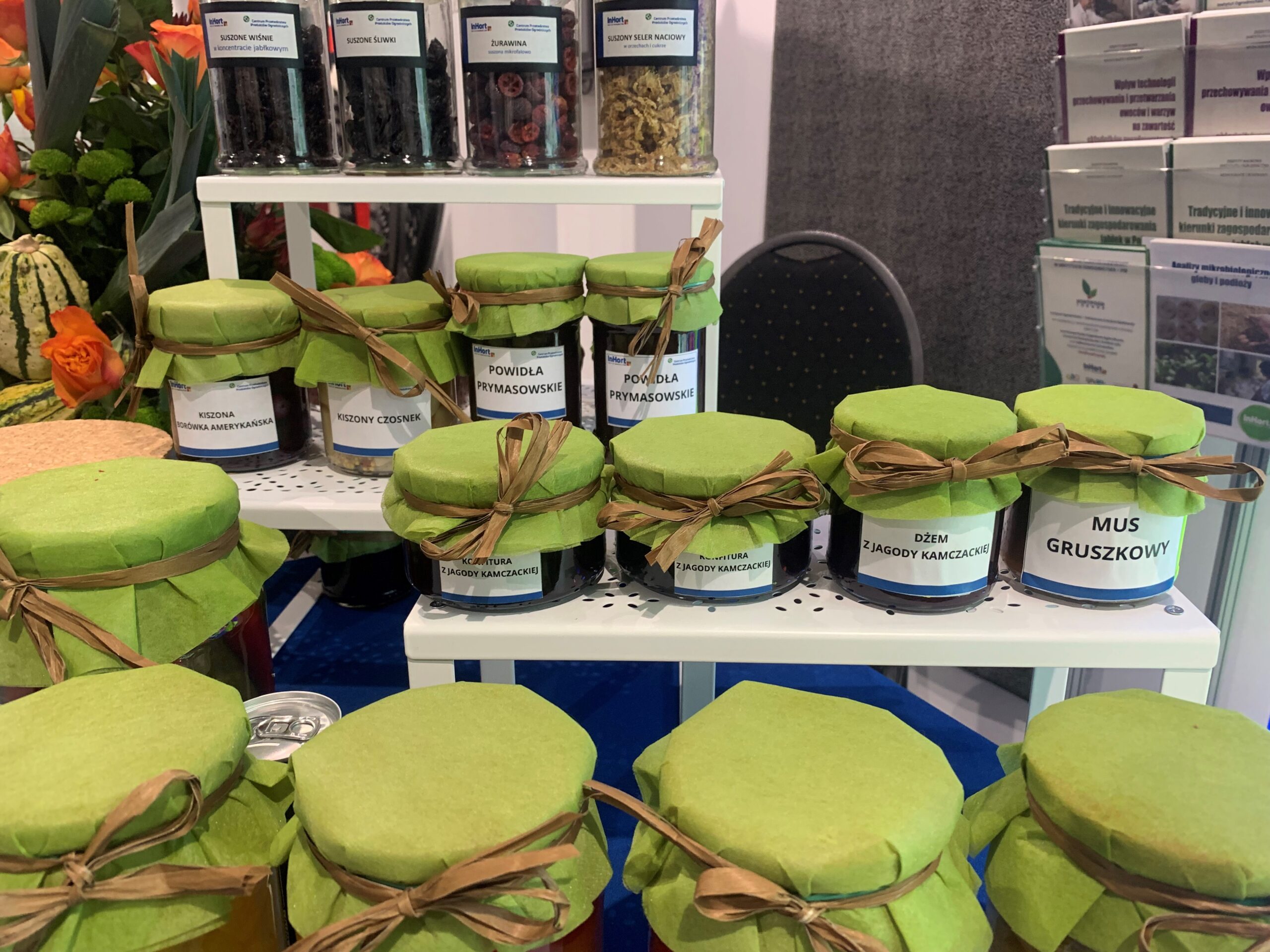 Display of artisanal preserves in glass jars with green fabric covers, featuring products like pear mousse and jam made from Kamchatka berries.